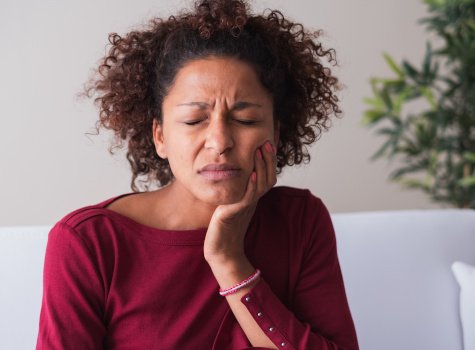 Woman with toothache sitting on couch at home