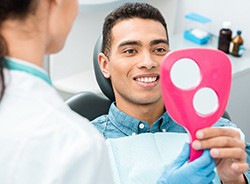 Man smiling at reflection in handheld mirror