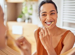 Woman smiling while brushing her teeth