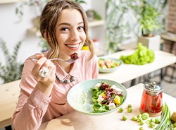 Closeup of woman smiling while eating salad at home